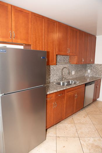A kitchen with a stainless steel refrigerator and wooden cabinets.